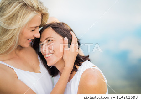 Adult daughter spending time with her mother outdoors. Beautiful daughter holding mother's face lovingly. Unconditional, deep maternal love, Mother's Day. 114262598