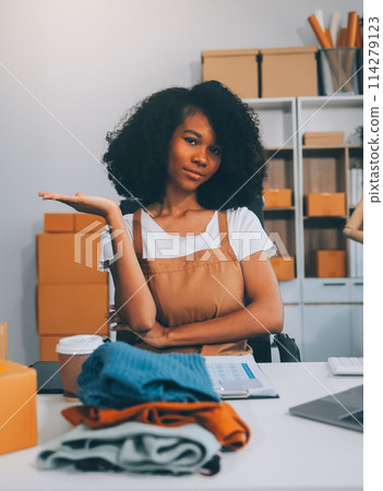 Startup SME small business entrepreneur of freelance Asian woman wearing apron using laptop and box to receive and review orders online to prepare to pack sell to customers, online sme business ideas. 114279123