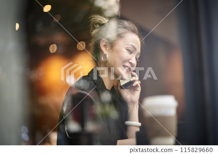 asian woman talking on cellphone in coffee shop 115829660