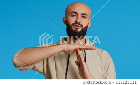 Middle eastern person doing timeout gesture on camera, asking for a break to stop working over blue background. Muslim adult presents symbol to pause or stop something. Camera 2. Handheld shot. 115123111