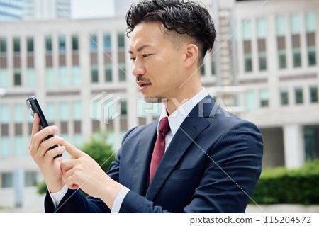 Urban businessman operating a smartphone 115204572