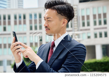 Urban businessman operating a smartphone 115204573