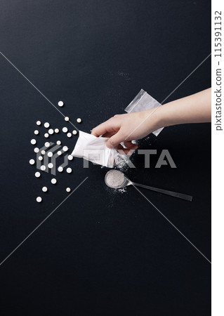 a hand holding a plastic bag containing drugs 115391132