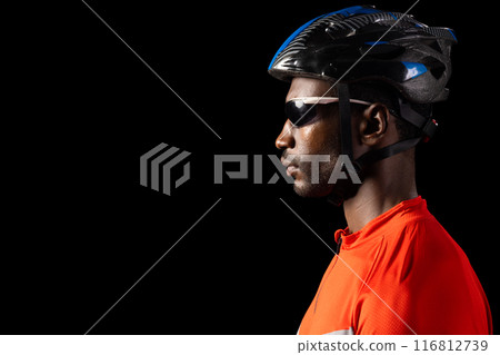 African American man in cycling gear poses confidently on black background, with copy space 116812739