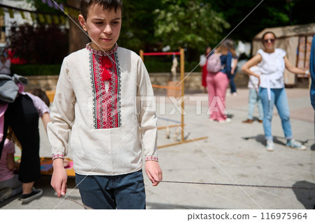 Boy in traditional embroidered shirt at outdoor cultural event 116975964