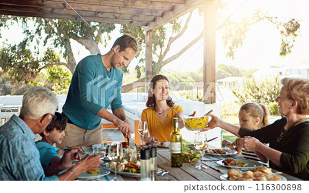 Happy family, eating and lunch with bonding outdoor on patio with conversation, relax or hosting healthy food. Parents, grandparents and kids at dining table in backyard of home with talking and fun 116300898