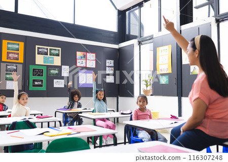 In school, young biracial female teacher is engaging with diverse students in the classroom 116307248