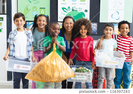 In school, diverse group of students and their teacher holding recycling materials in the classroom 116307283