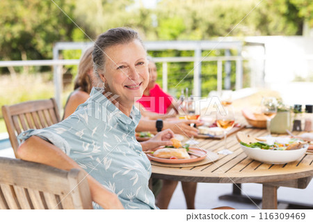 Diverse senior female friends sharing meal outdoors 116309469