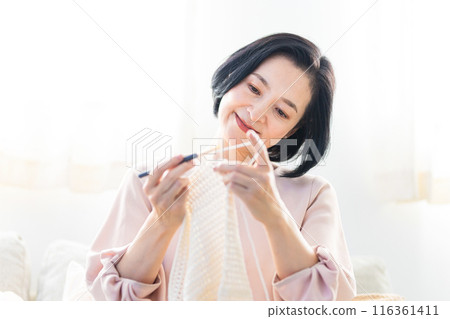 Senior woman knitting in the living room 116361411