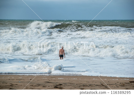 A man alone swims in the Atlantic Ocean in a storm, big waves, danger on the beach 116389295