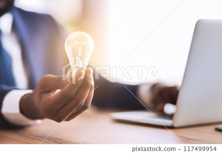 African american businessman with illuminated light bulb, concept for idea, innovation and inspiration, cropped 117499954