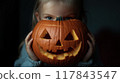 A child holds a carved pumpkin with a smiling face, showcasing Halloween spirit during the evening festivities. Generative AI 117843547