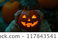 A child holds a carved pumpkin with a glowing face during a Halloween celebration on a cool autumn evening. Generative AI 117843541