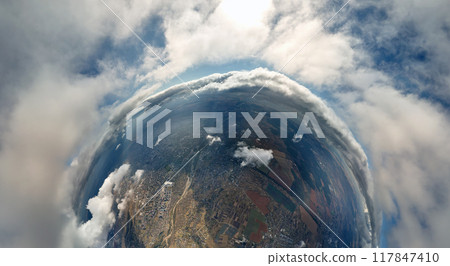 Aerial view from high altitude of little planet with distant city covered with puffy cumulus clouds forming before rainstorm. Airplane point of view of cloudy landscape 117847410