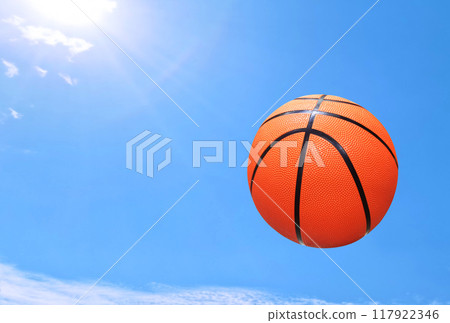 A basketball flies through the air with the sky in the background. 117922346