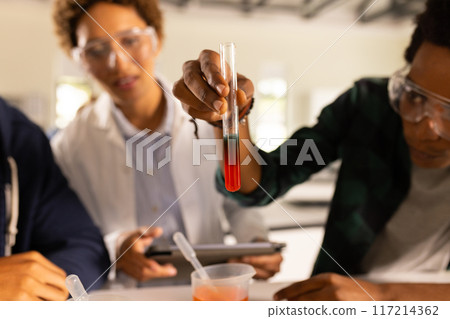 In high school, students conducting science experiment with test tube and pipette 117214362