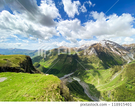 Beautiful landscape with mountains and peaks in the snow and a valley with roads and a lake  118915401