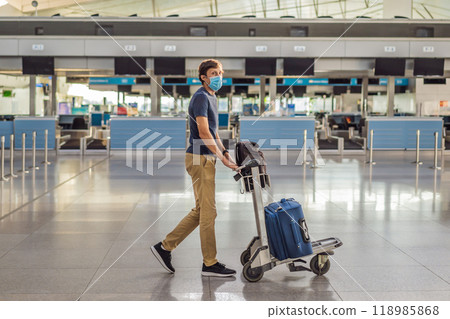 Man in mask at empty airport at check in in coronavirus quarantine isolation, returning home, flight cancellation, pandemic infection worldwide spread, travel restrictions and border shutdown 118985868