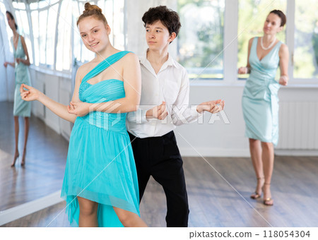 Girl and boy in evening dresses learn to dance the foxtrot in choreographic studio 118054304