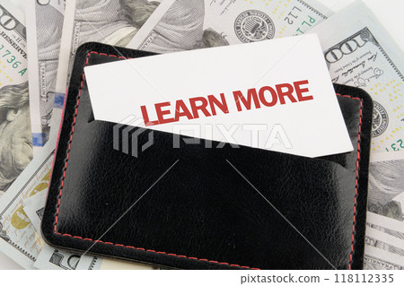 LEARN MORE text on business cards in a business card holder against the background of American dollar bills 118112335