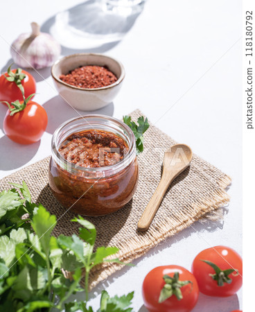 Homemade tomato sauce is an appetizer with tomatoes and hot peppers in a jar on a light background  118180792