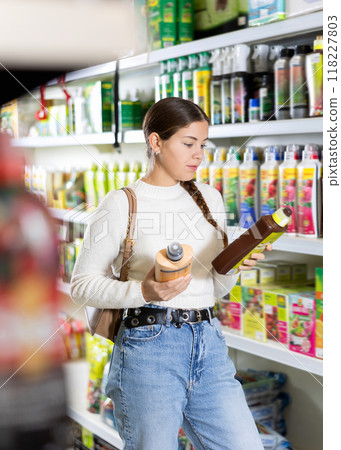 Young woman choosing fertilizers in hardware store 118227803