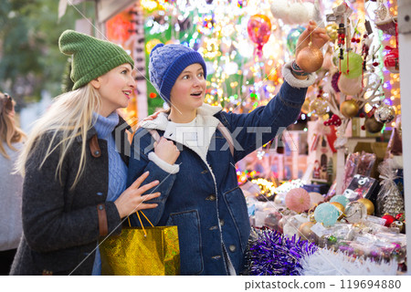 Happy mother with daughter choosing Christmas decoration and balls at Christmas market 119694880