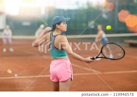 Two young women playing tennis against elderly women 119948578