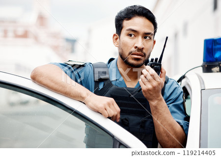 Asian man, police and walkie talkie for radio in city communication, reinforcement or emergency. Serious male person or security guard by cop car and calling backup for crime on patrol in urban town 119214405