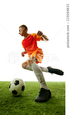 In motion, football player controls ball with expert precision, navigating green field in graceful athletic stance, ready to make next move. 119264631