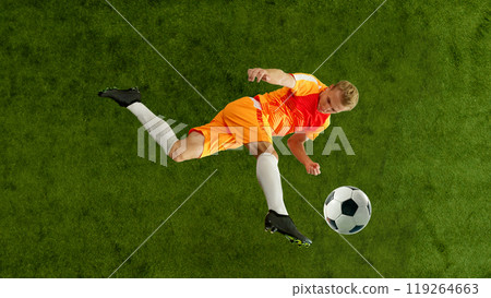 Football player kicks ball in motion demonstrating strength and technique. Professional footballer connects with ball mid-air. 119264663