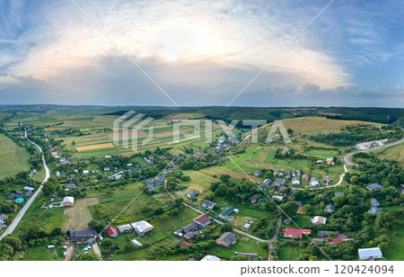 Aerial landscape view of green cultivated agricultural fields with growing crops and distant village houses 120424094