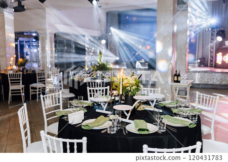 Elegant banquet hall setup with floral centerpieces, candles, and stylish table arrangements 120431783