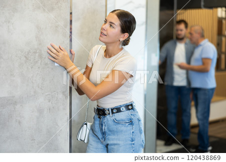 Girl looking to buy floor ceramic tiles in materials section of store 120438869