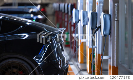 EV charger and electric car, Electric car charger station for charge ev battery, Plug for vehicle with electric engine, EV charger clean energy, Charging point at car parking lot department store. 120477178