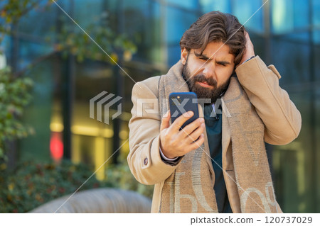 Upset Indian man using smartphone browsing, loses becoming shocked bad news on downtown city street 120737029