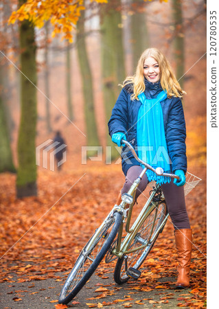 Happy active woman riding bike in autumn park. 120780535