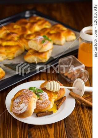 Pastries. Sweet buns with cottage cheese filling and honey in a plate on a wooden table 120816938