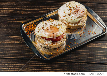 Freshly fried egg on rice bread with tomato and feta cheese on a metal tray 120968278