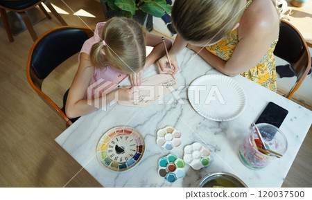 A young mother and her daughter enjoy a creative art session at home  120037500