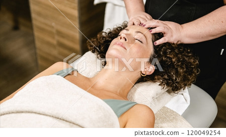 Masseuse giving relaxing head massage to client in spa 120049254