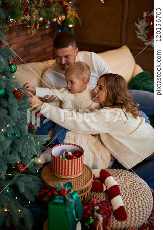 Happy family decorate the Christmas tree and smiling cheerfully on Christmas Eve in a beautiful home 120156703