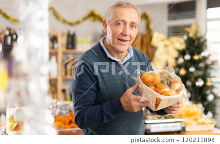 Elderly man chooses tangerines in grocery store 120211093