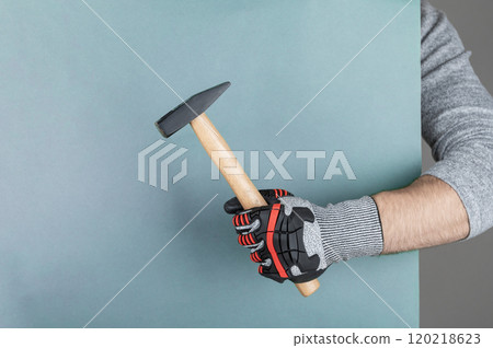 Hand with protective glove holding hammer 120218623