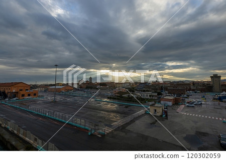 Morning scene at Livorno harbor with ferry at sunrise cloudy sky and sun rays reflecting on water 120302059