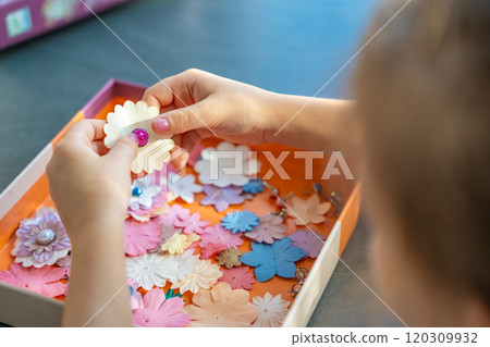 Small, colorful paper flowers in child hands, little girl creativing of 3D flowers. Child development toy 120309932