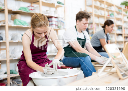 Girl teenager learns how to create pottery in workshop 120321698