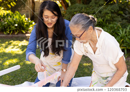 Painting together outdoors, asian granddaughter and grandmother enjoying creative activity 120368703