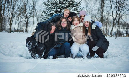 Schoolgirls having fun and enjoying the winter holidays in a snowy park, posing together cheerfully 120382530